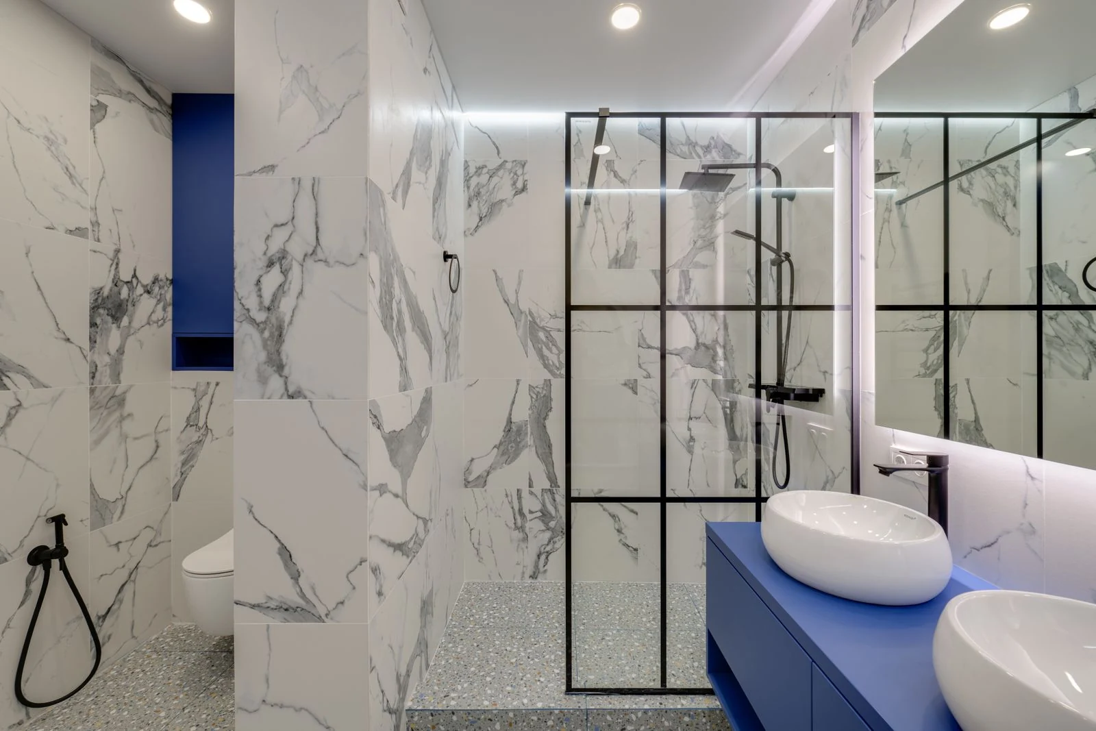 Elegant bathroom featuring marble walls, double sinks, and a glass-enclosed shower