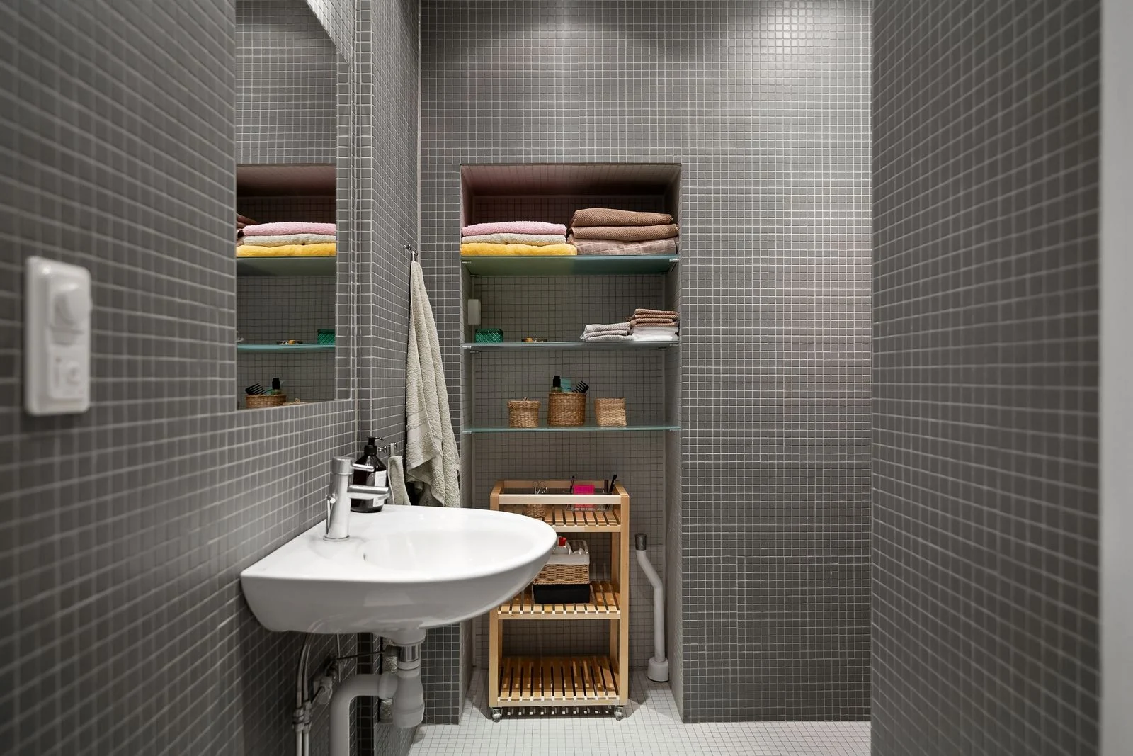 Small washbasin beside open shelves