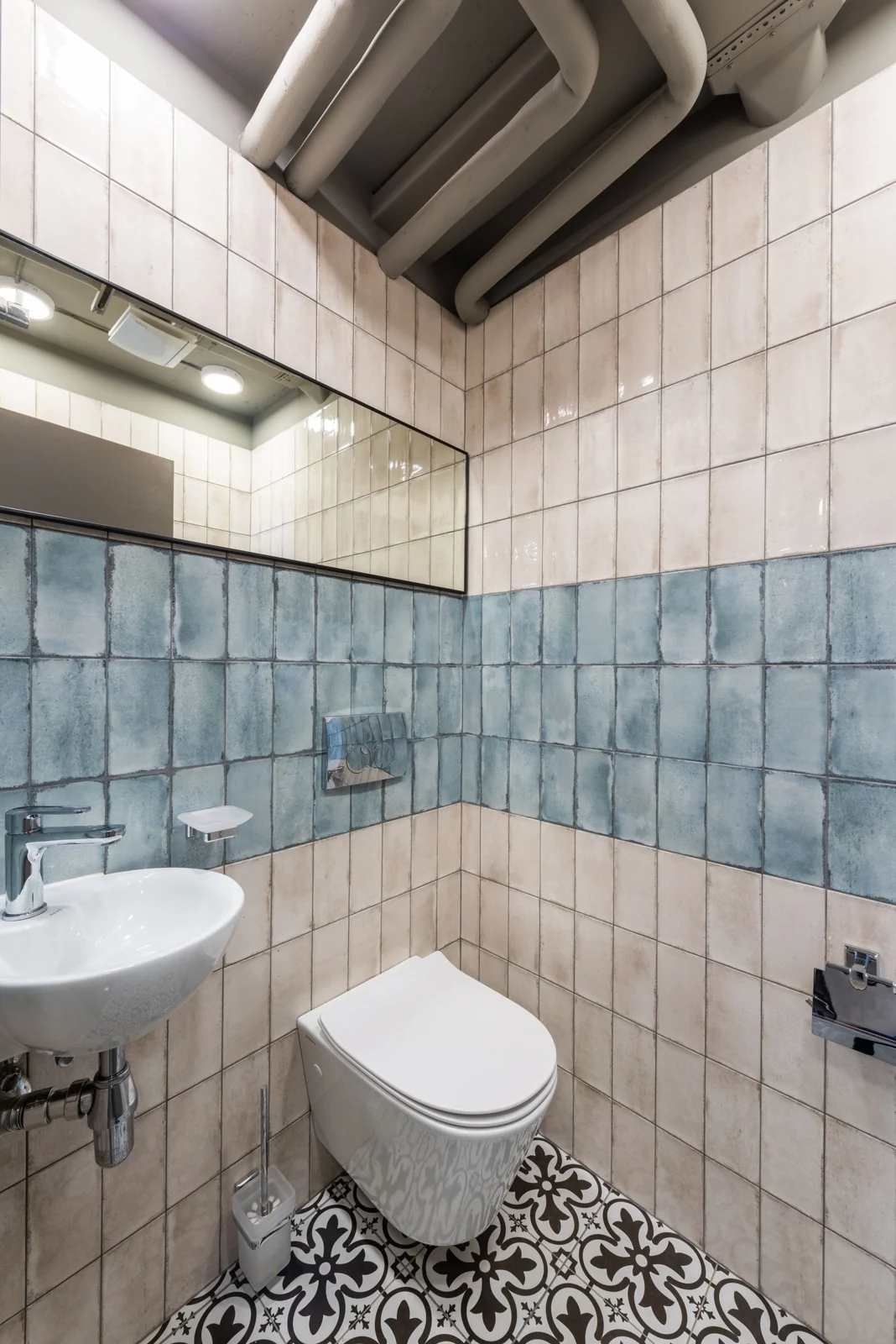 Modern creative interior of restroom with ornamental tiled floor and walls and ceramic sink and toilet