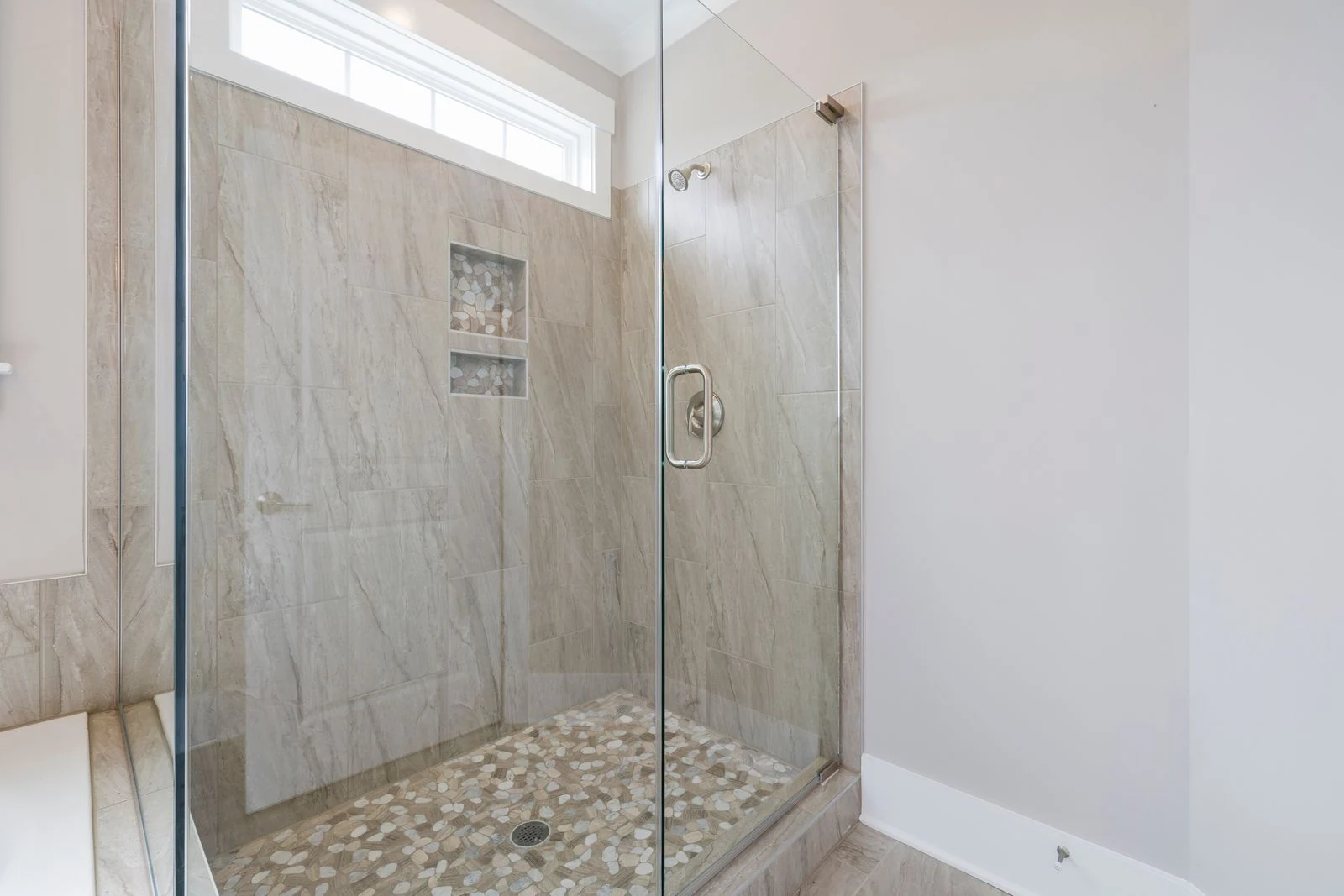 Spacious luxury bathroom featuring a contemporary marble shower with glass doors, combining elegance and modern design