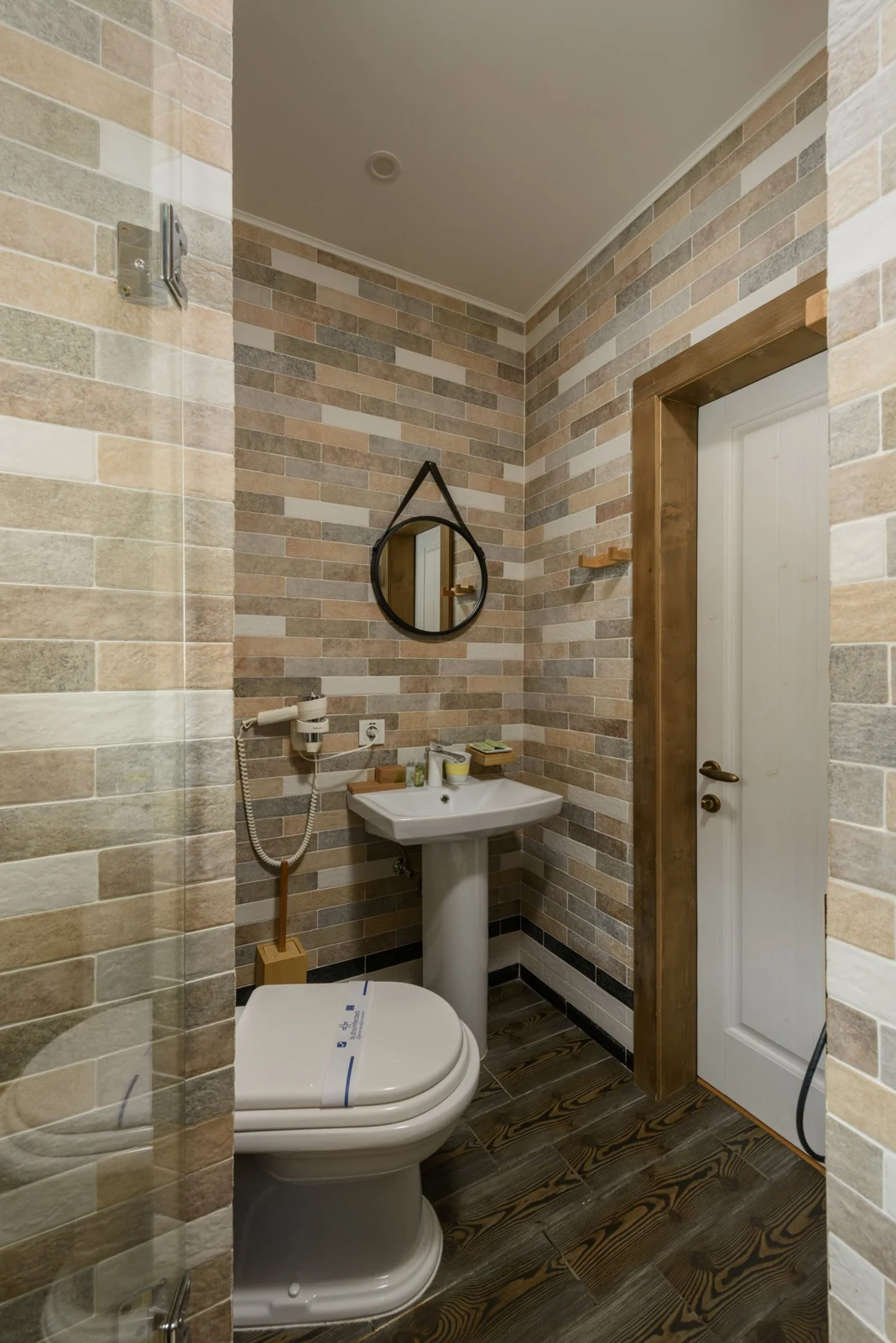 A contemporary restroom with geometric tiles, white sink, and round mirror