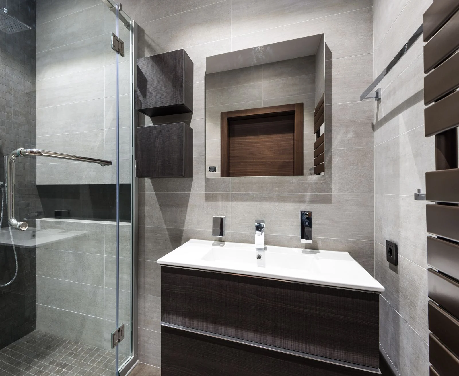 Stylish modern bathroom featuring dark wood elements, sleek sink, and glass shower