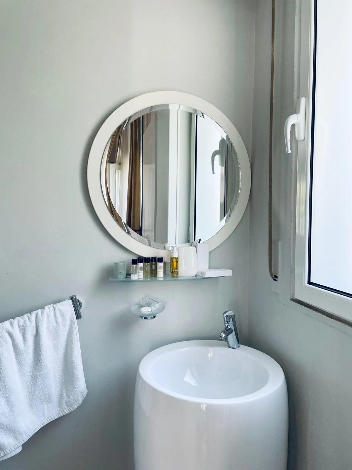 Small pedestal basin below a round mirror